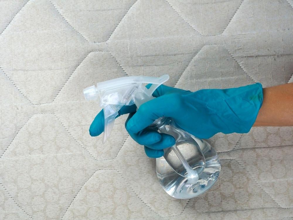 Čistenie matraca octom vo fľaši s rozprašovačom na odstránenie pachov a baktérií