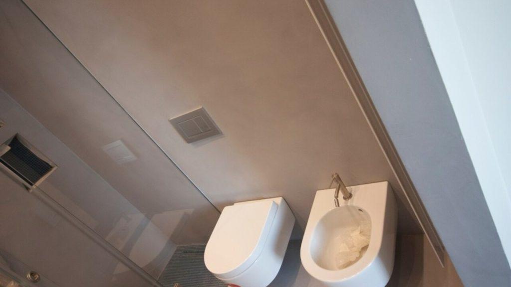 Moderná kúpeľňa so stenami z mikrocementu, toaleta a bidet v minimalistickom dizajne.