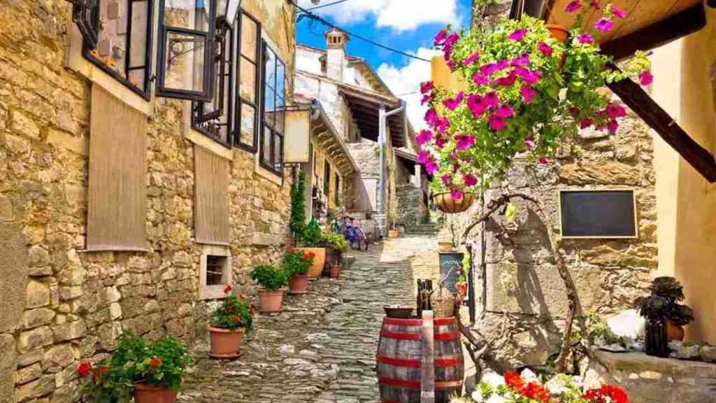 Farebná kamenná ulička mesta Hum na Istrii v Chorvátsku s kvetmi a historickými domami