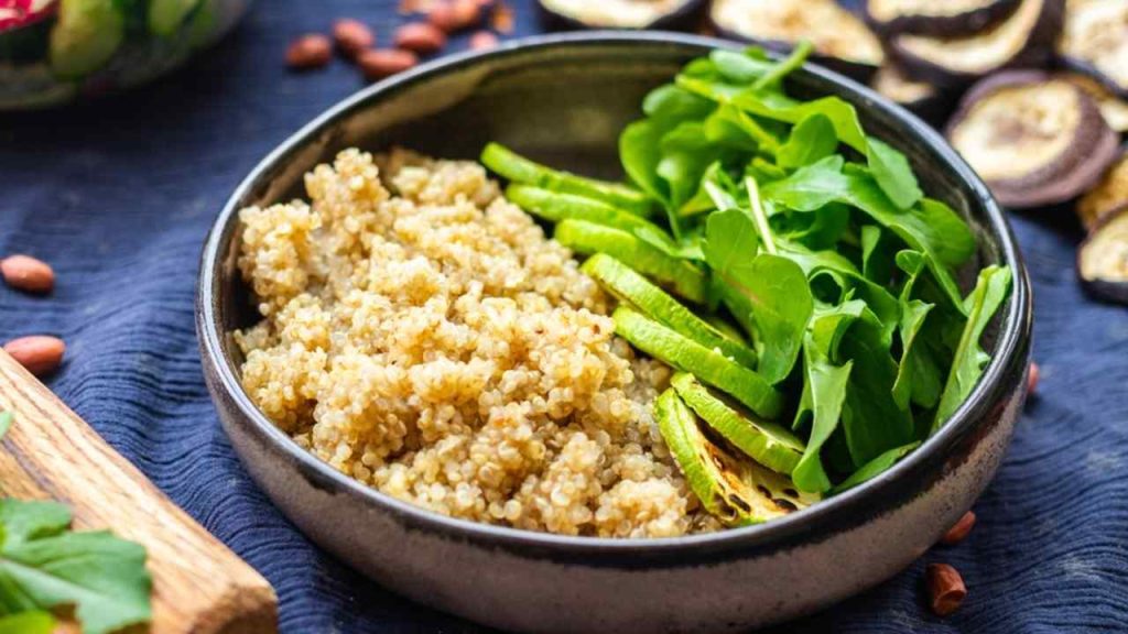 Miska s varenou zmesou amarantu a quinoy, cuketou a rukolou – vyvážené vegánske jedlo plné bielkovín a vlákniny.