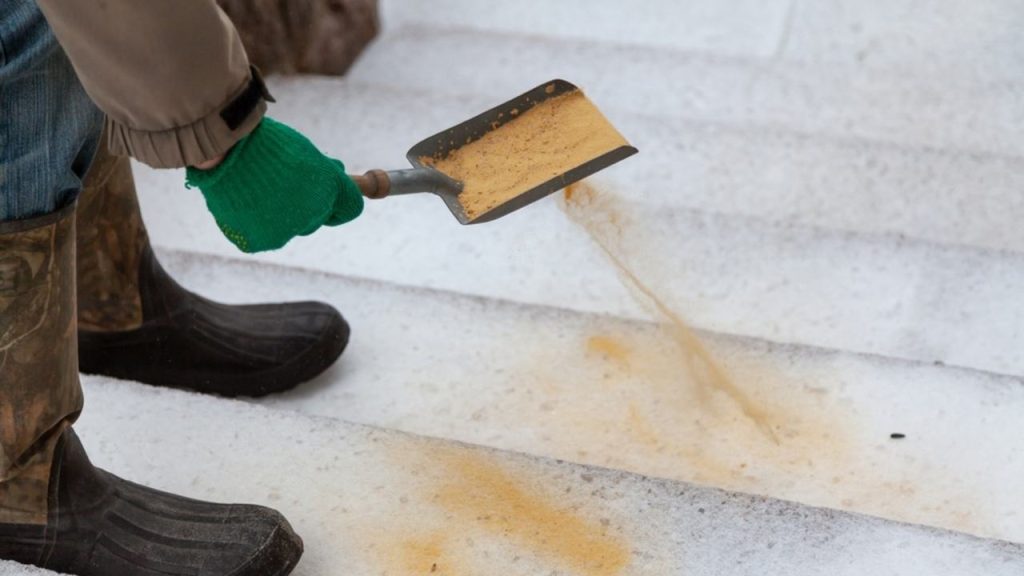 Posýpanie zľadovatených schodov pieskom počas zimy.