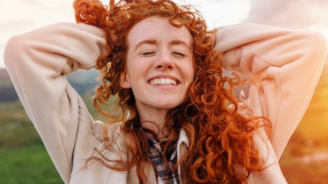 Usmievajúca sa žena na slnku symbolizujúca návrat radosti po prekonaní strachu.