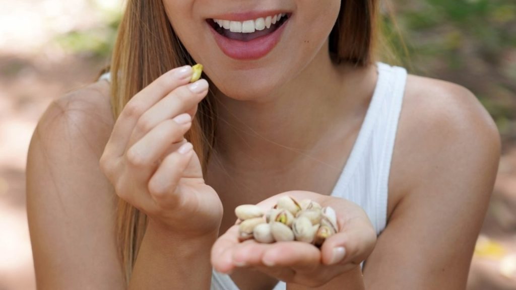 Žena si pochutnáva na pistáciách ako na zdravej desiate počas dňa.