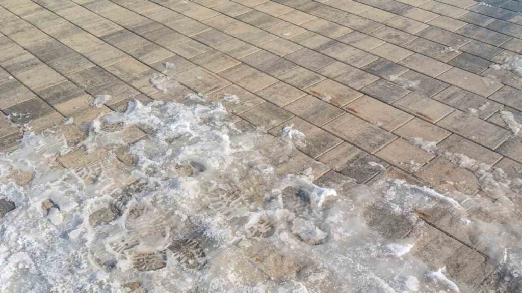 Zľadovatený chodník s vrstvou snehu a ľadu počas zimy.