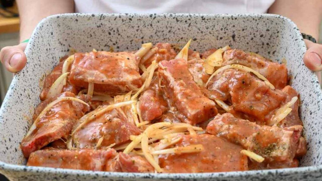 Marinované bravčové rebrá s cibuľou a korením pripravené v zapekacej mise pred pečením.