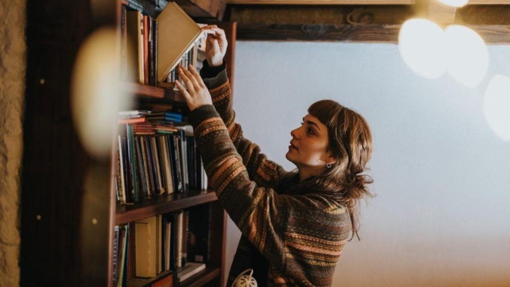 Polica plná papierových kníh v domácej knižnici.