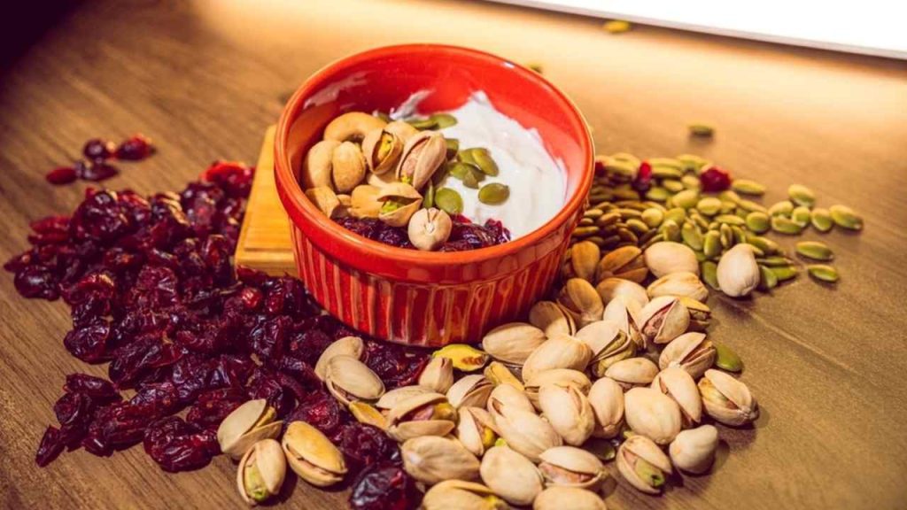Miska gréckeho jogurtu s čučoriedkami, pistáciami a slnečnicovými semenami ako lahodný zdravý dezert. Vegánske, orechy, zdravé jedlo, zdravé dezerty a semená.
