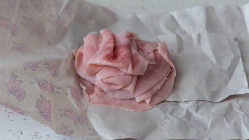 Plátky šunky zabalené v papieri, pripravené na správne skladovanie v chladničke.