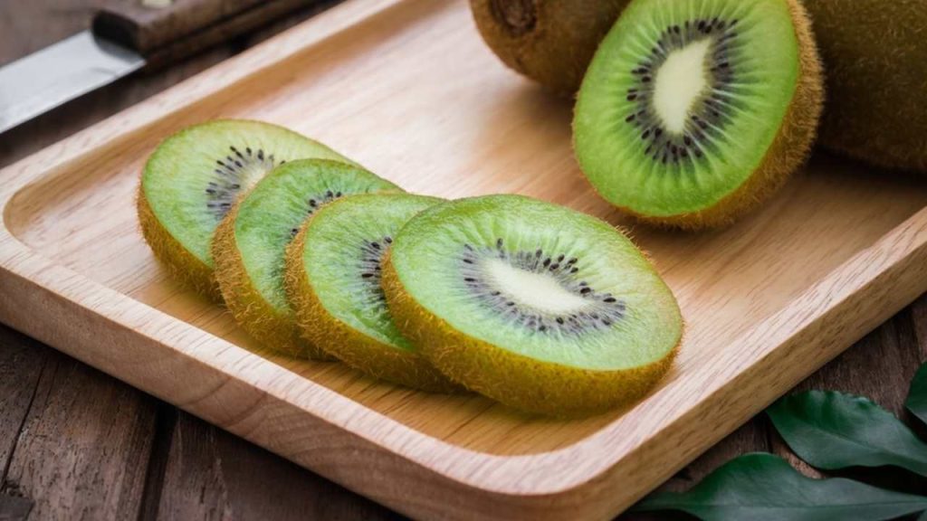 Čerstvé kiwi nakrájané na polovicu na drevenom stole.