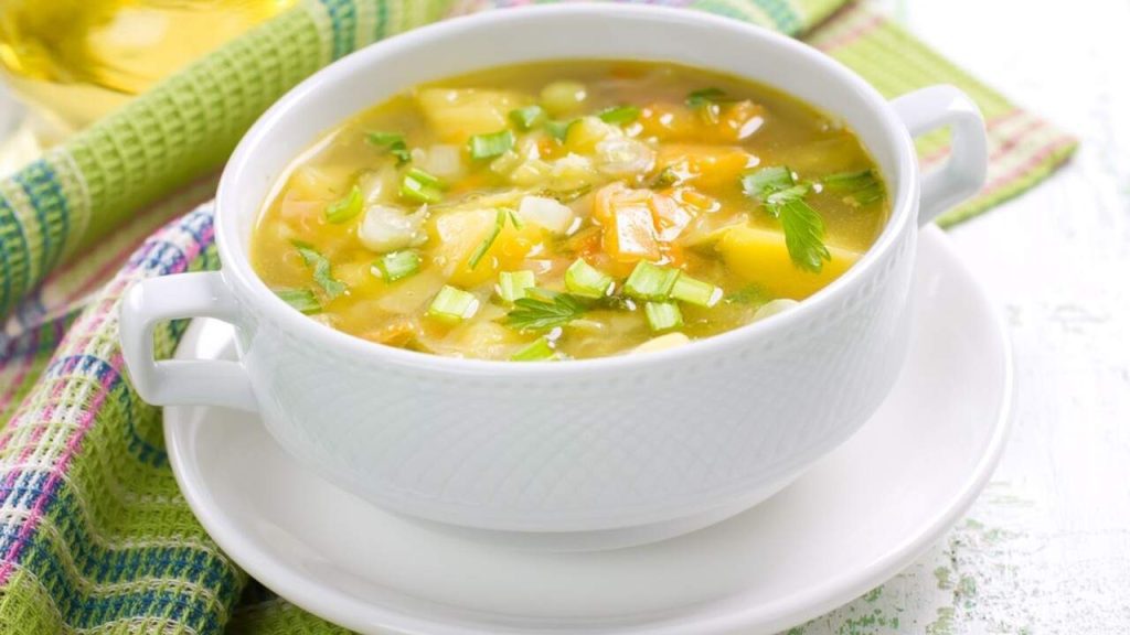 Zeleninová kapustová polievka s kúskami zemiakov, mrkvy a petržlenovou vňaťou podávaná v bielej miske