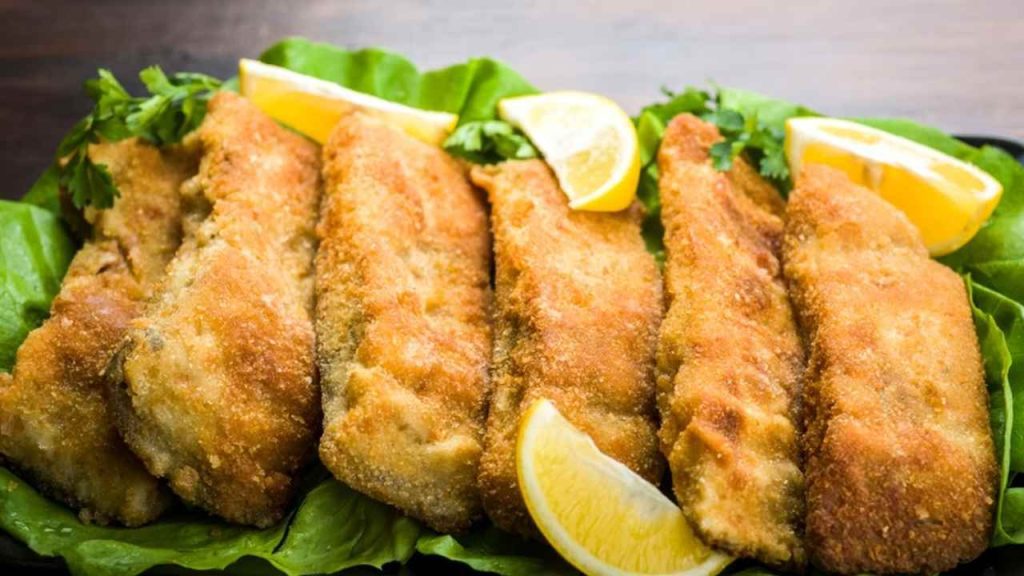 Hotové vyprážané filety kapra servírované so šalátom a citrónom