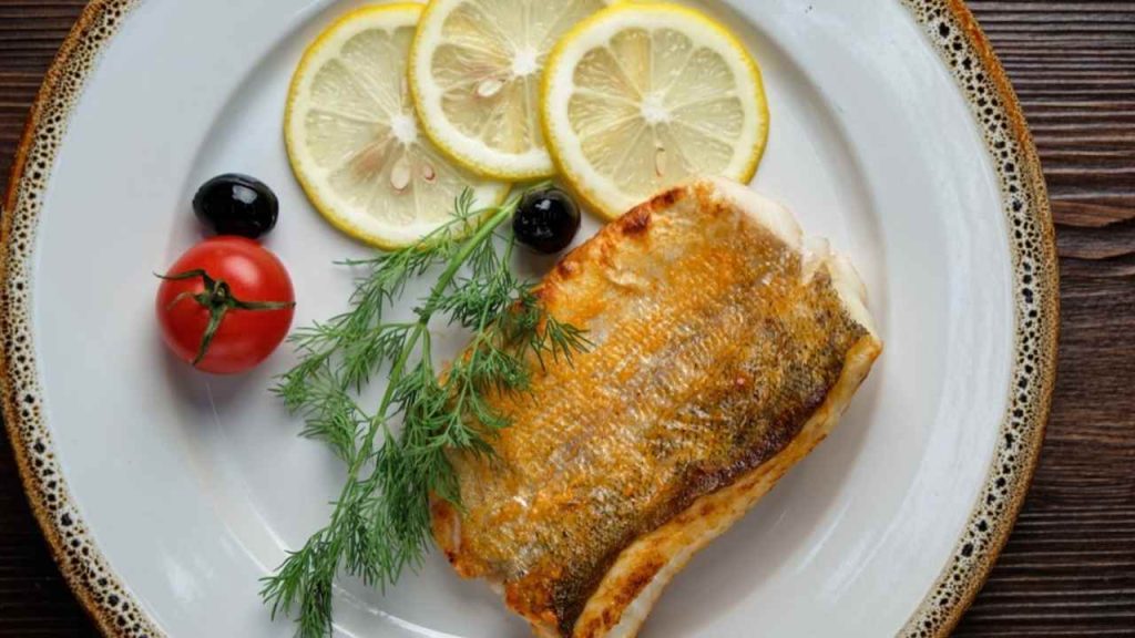 Biela ryba opečená na masle s citrónom a kôprom podávaná na tanieri