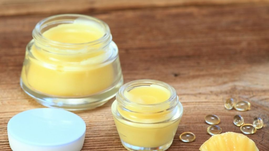 Hotový domáci balzam na pery v malých sklenených téglikoch na drevenom stole.