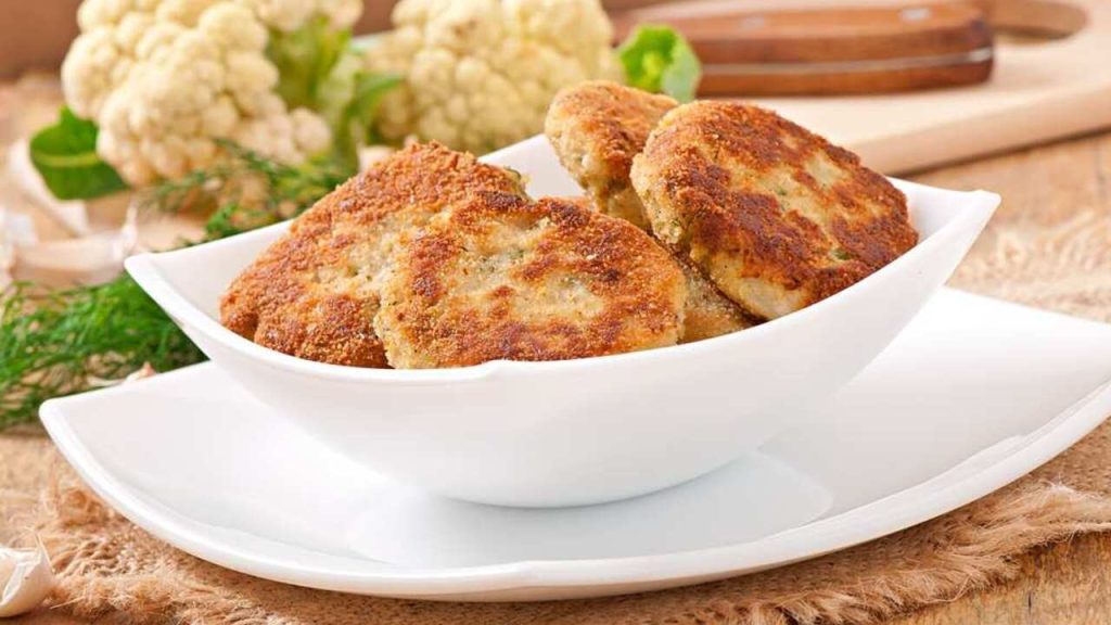 Karfiolové rezne so zemiakmi vyprážané dozlatista, servírované v miske