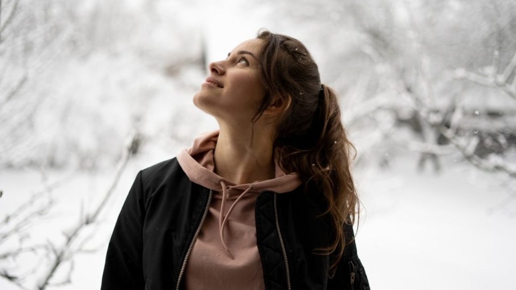 Žena stojaca v zasneženej prírode pozerá smerom hore, symbol mentálnej rovnováhy a vnútorného pokoja