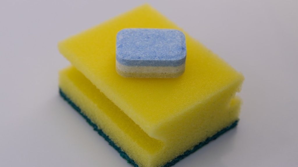 Tableta do umývačky položená na hubke na čistenie