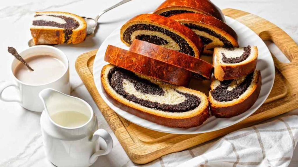 Nakrájaný makový koláč na tanieri podávaný s teplým nápojom