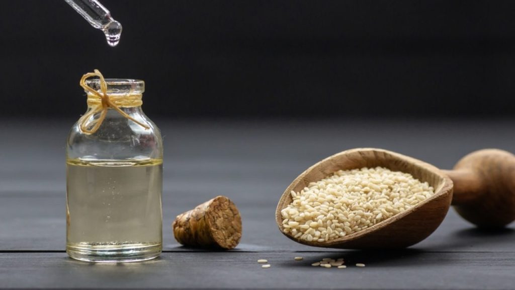 Sezamový olej v sklenenej fľaštičke so sezamovými semienkami ako prírodný elixír pre pokožku