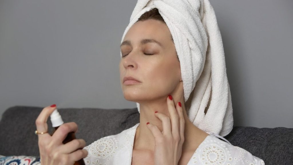 Žena si v zime aplikuje pleťové tonikum v spreji pre okamžitú hydratáciu a úľavu