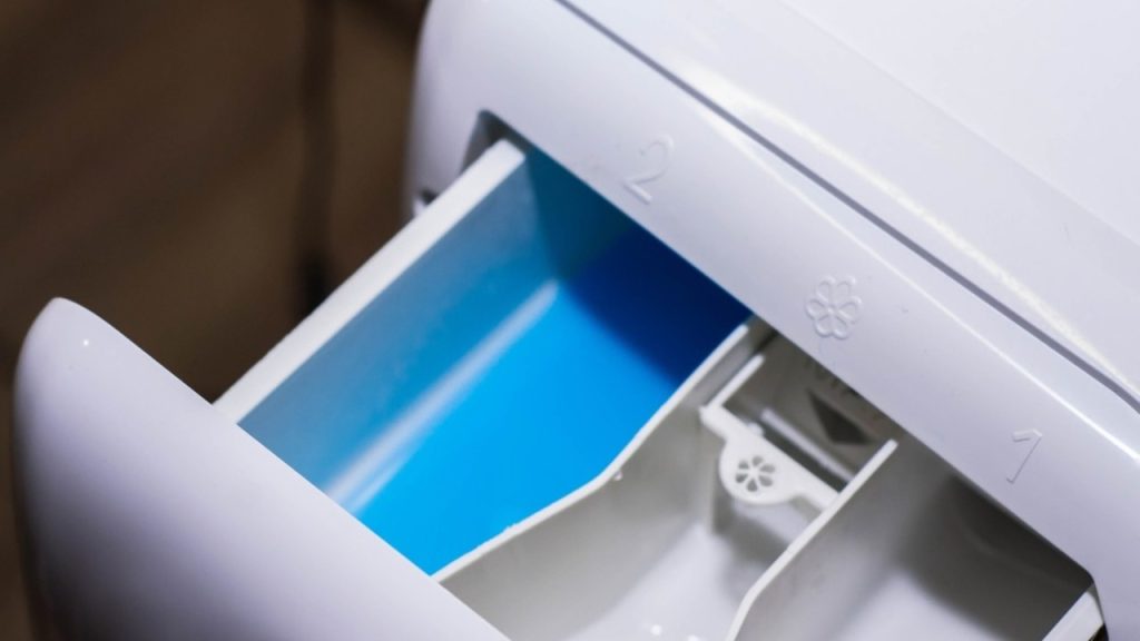 Vysunutá zásuvka práčky na prací prostriedok, pripravená na preschnutie po praní.