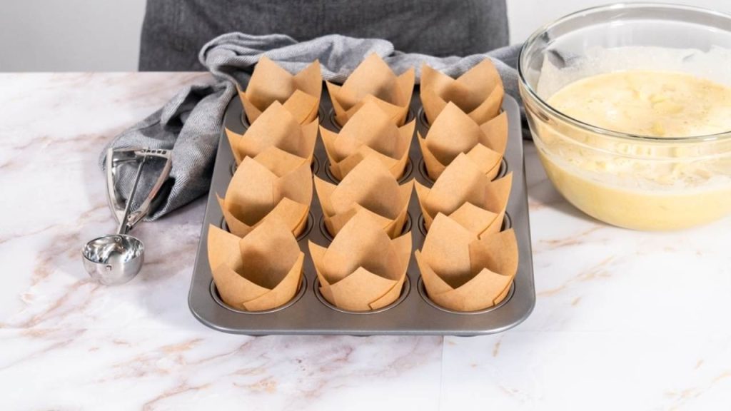 Pripravené papierové košíčky na jablkové muffiny v plechu na pečenie