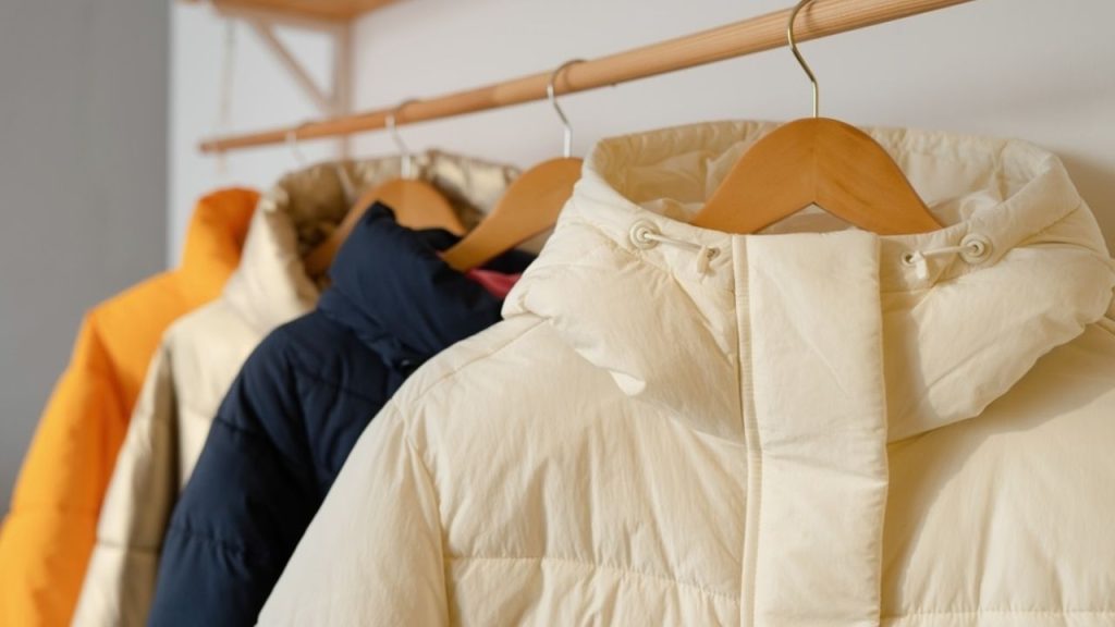 Páperové bundy zavesené na vešiaku v interiéri po šetrnom čistení