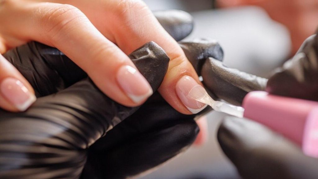 Aplikácia jemného trblietavého laku na nechty v štýle twinkle nails počas profesionálnej manikúry