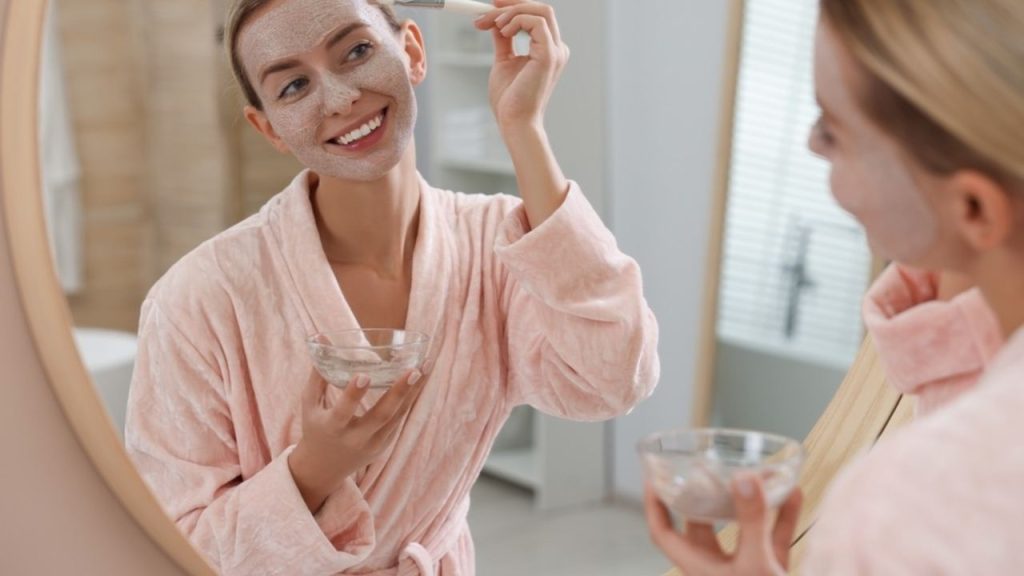 Žena nanášajúca domácu pleťovú masku pred zrkadlom ako rýchly beauty rituál