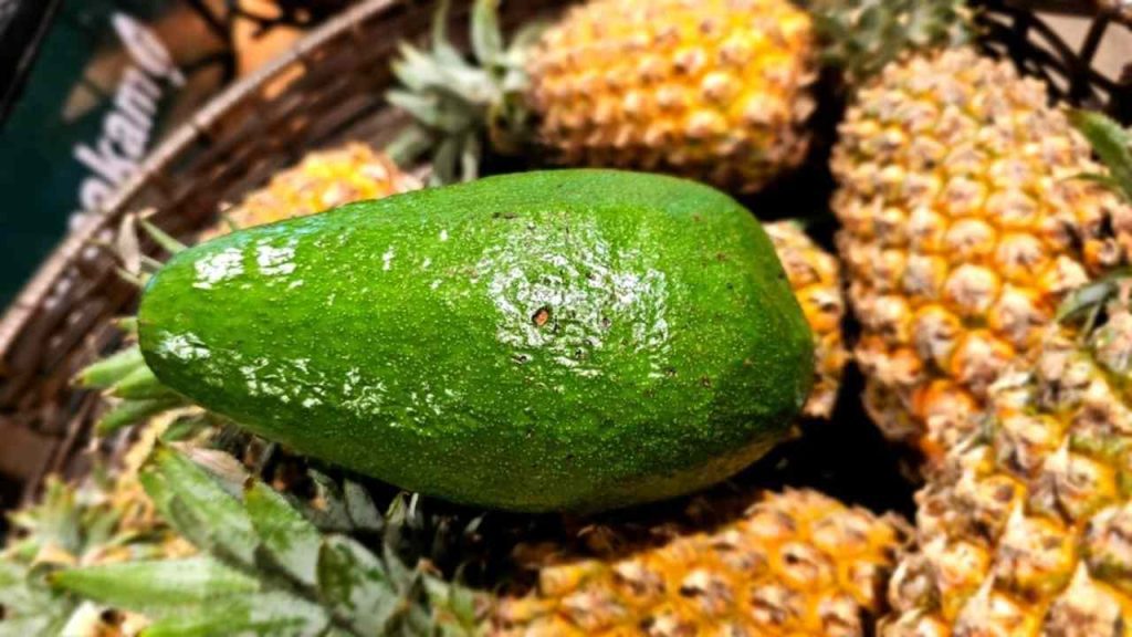 Avokádo položené medzi ananásmi, potraviny s prirodzenou ochranou pred pesticídmi.