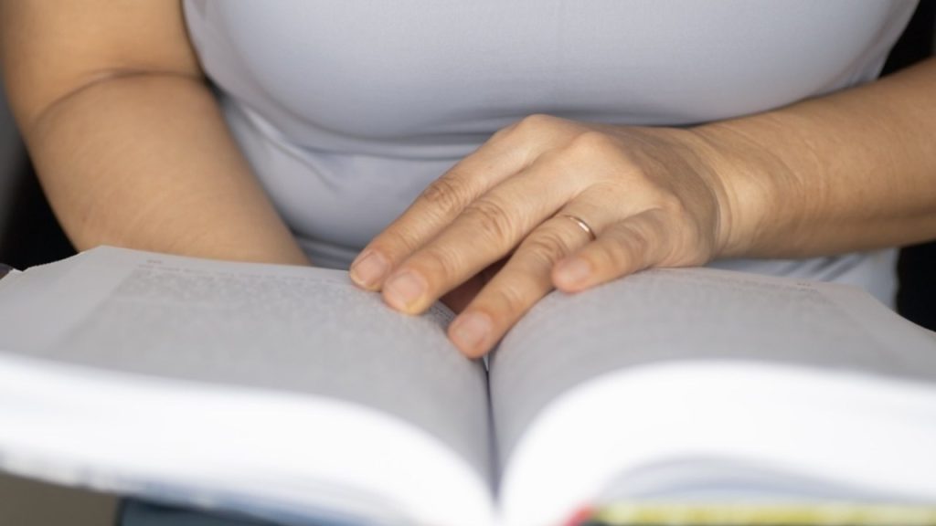 Osoba v strednom veku číta knihu ako symbol celoživotného učenia a rastu múdrosti.