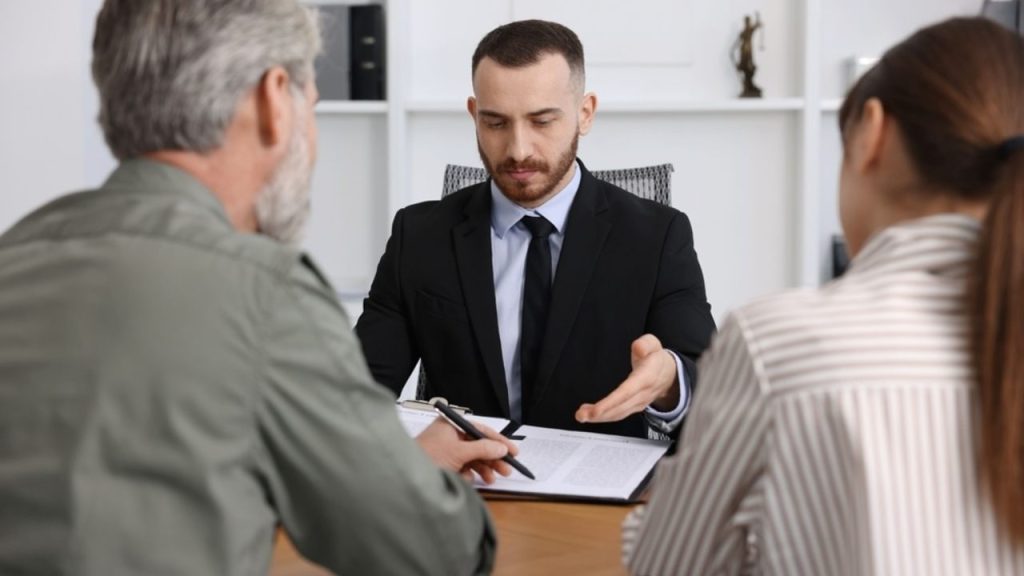 Notár pri stole podpisuje dokumenty súvisiace so závetom.