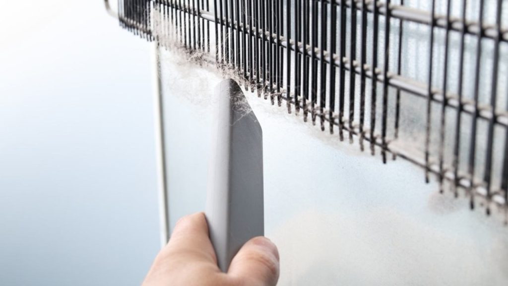 Čistenie zanesených cievok kondenzátora na zadnej strane chladničky pomocou úzkej hubice vysávača.