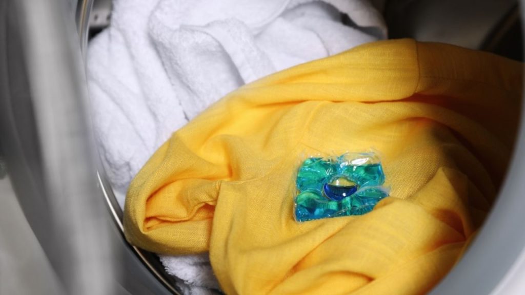 Pracia kapsula položená na oblečení v bubne práčky pred praním