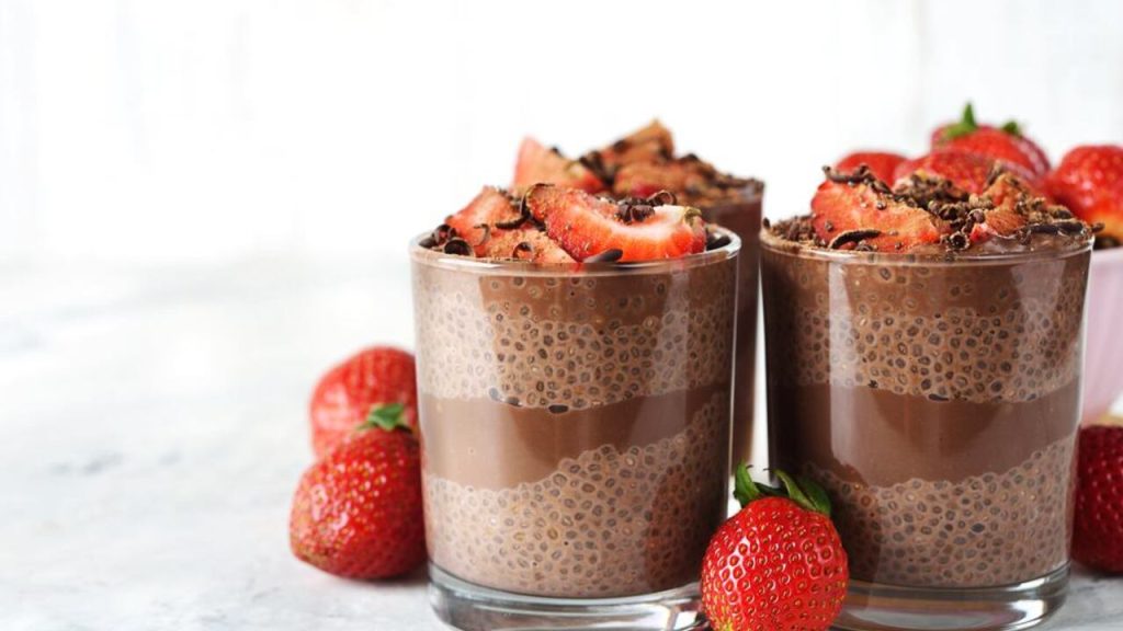 Čokoládový chia puding v sklenených pohároch s jahodami a kakaovými hoblinami