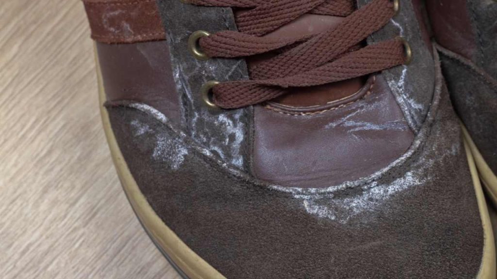 Zimné topánky so soľnými škvrnami a bielymi mapami na semiši po chôdzi po posypaných chodníkoch