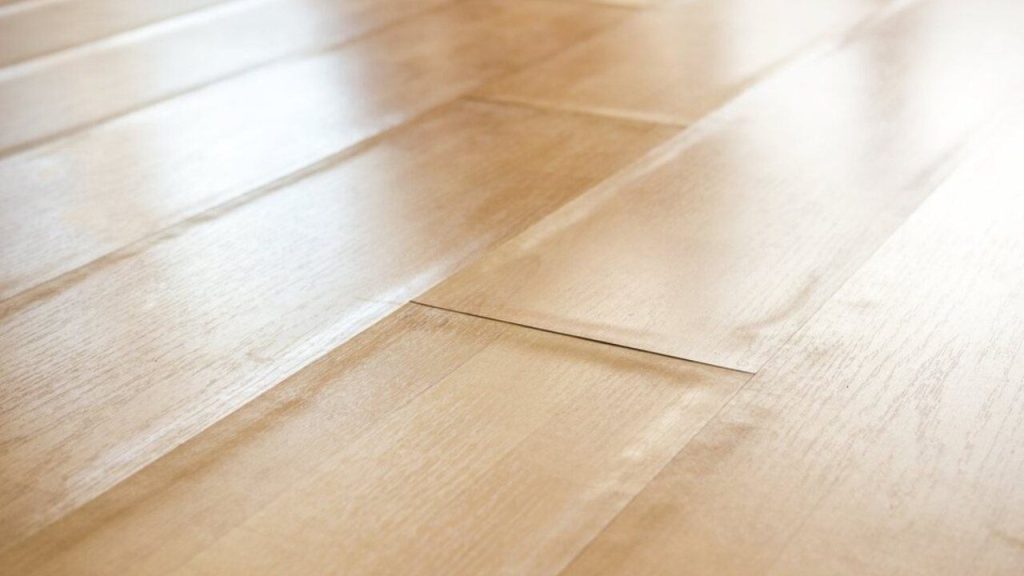 Poškodená laminátová podlaha s vyduvaniami od vlhkosti
