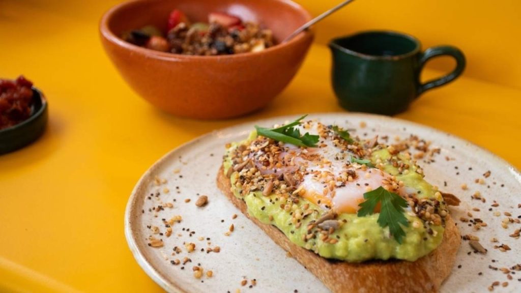 Zdravé raňajky s vysokým obsahom bielkovín – toast s avokádom, vajíčkom s tekutým žĺtkom, jogurt s ovocím a granolou