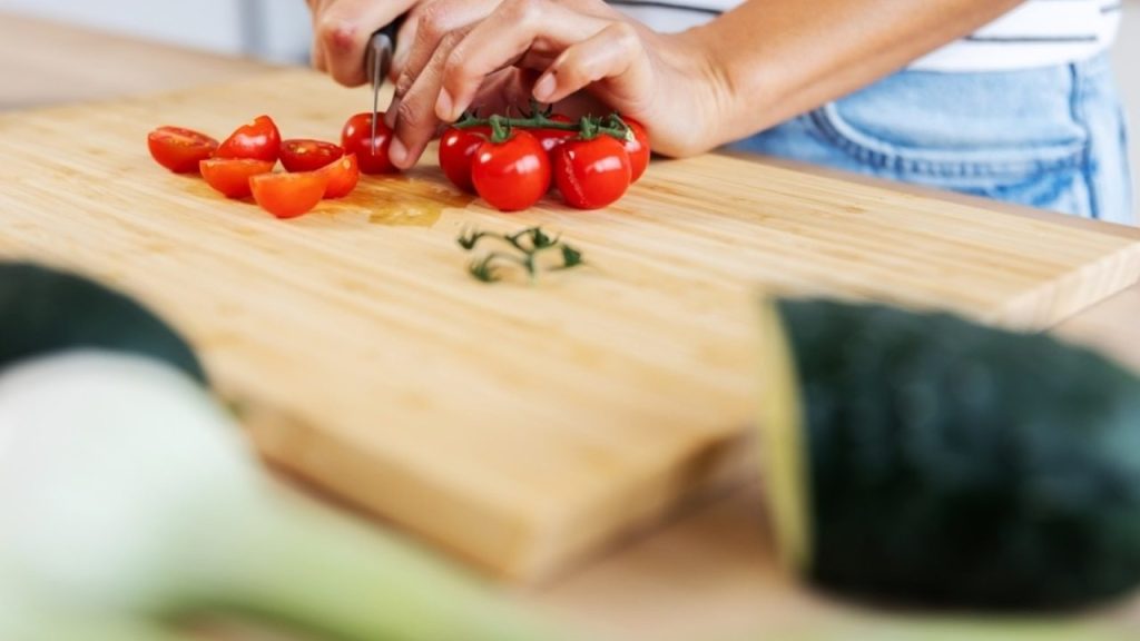 Krájanie zeleniny na drevenej doske v kuchyni – oddelená doska pre bezpečnú prípravu jedla