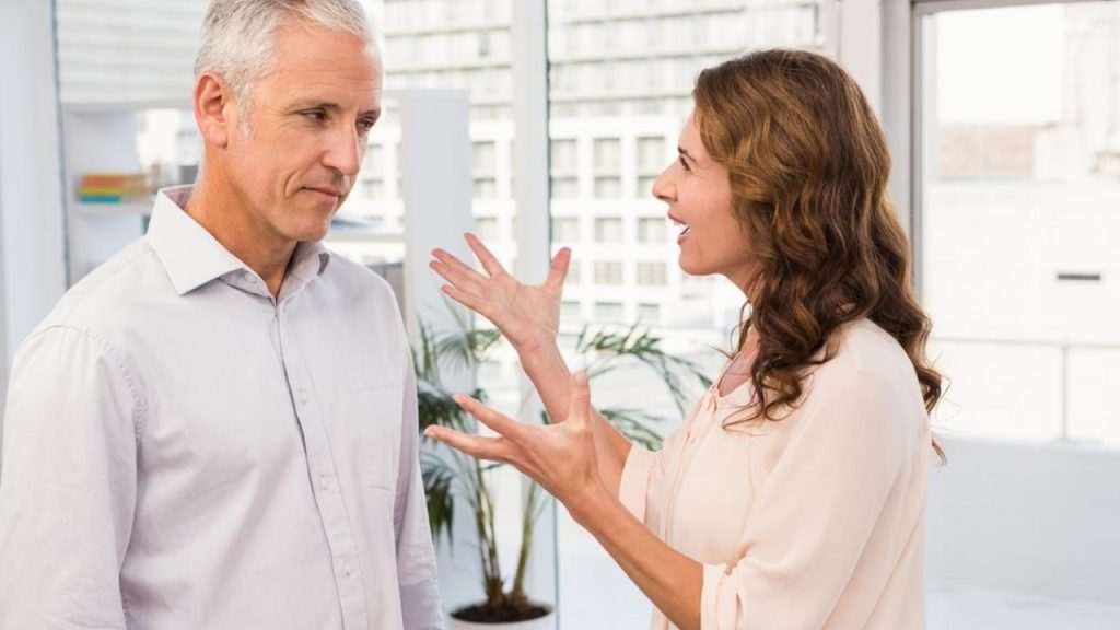 Muž a žena v kancelárii počas rozhovoru, napätá komunikácia a čítanie reči tela