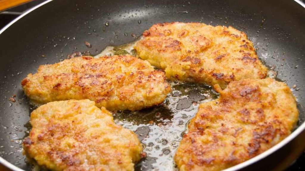 Vyprážané zlatisté rezne na panvici, opekané dozlatista na oleji