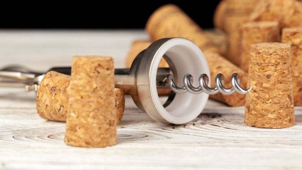 Vývrtka na víno položená medzi viacerými korkovými zátkami na drevenom stole