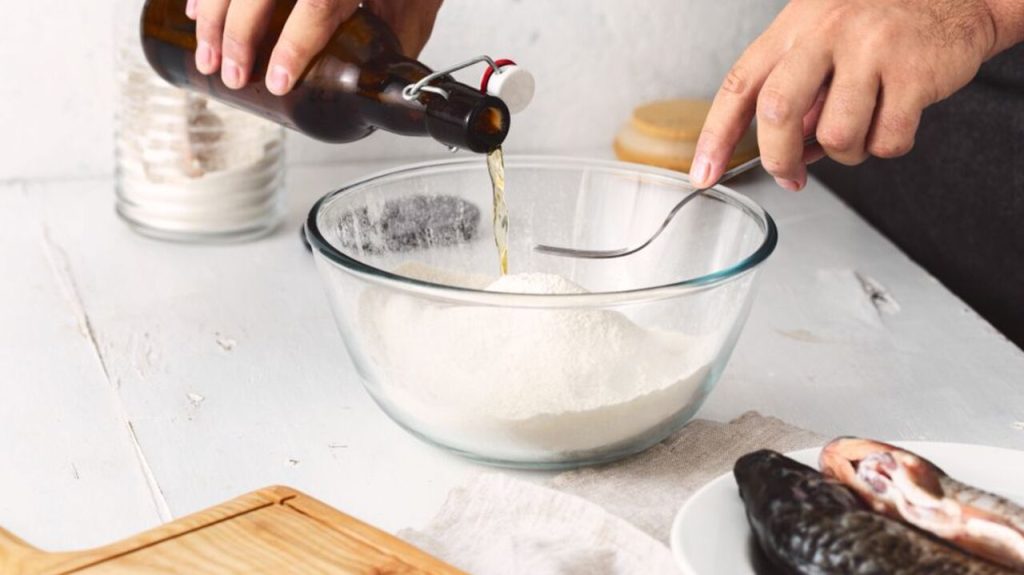 Príprava pivného cesta na rybu – nalievanie tmavého piva do misy s múkou