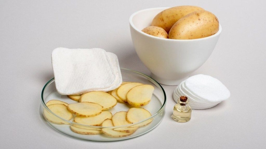 Plátky surového zemiaka, kozmetické tampóny a celé zemiaky pripravené na prírodnú starostlivosť o očné okolie