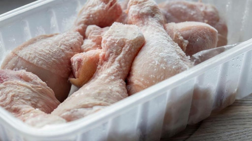 Zamrznuté kuracie stehná v plastovej nádobe pripravené na rozmrazovanie