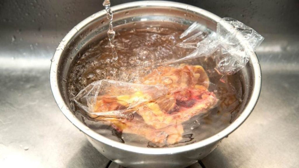 Mäso vo vzduchotesnom plastovom vrecku ponorené v miske so studenou vodou počas rozmrazovania