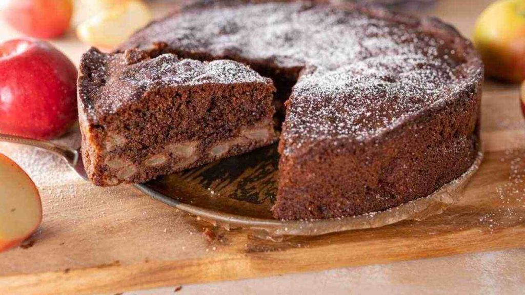 Čokoládový koláč s kúskami jabĺk posypaný práškovým cukrom, nakrájaný na kúsky na podnose