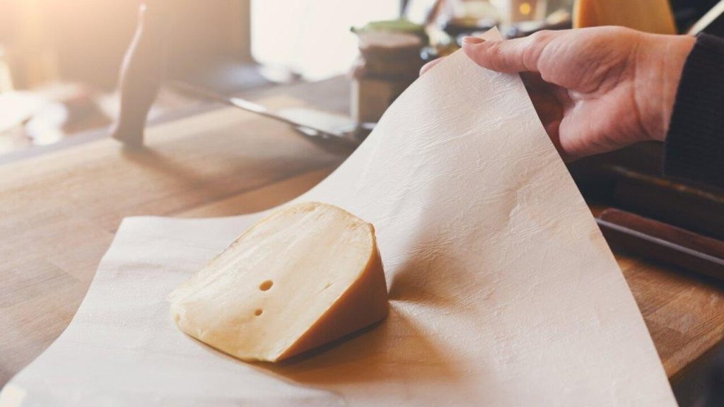 Kúsok tvrdého syra položený na papieri na pečenie pripravený na zabalenie a skladovanie