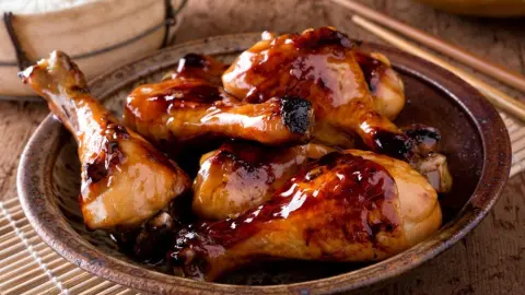 A bowl of delicious honey garlic chicken drumsticks with rice.