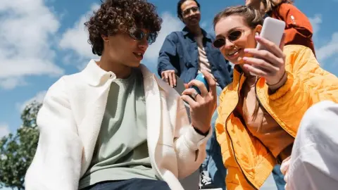 low angle view of curly man holding soda can near smiling interracial friends