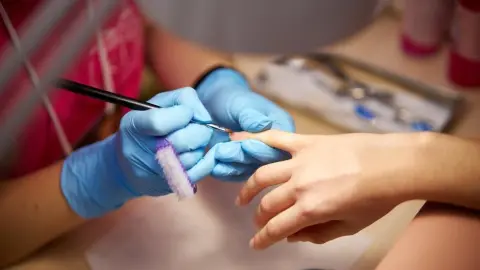 Women's manicure. Female hand undergoing a manicure procedure. The master does a women's manicure. A manicurist files a women's nails in a salon. Hygiene and hand care for woman. manicure design.
